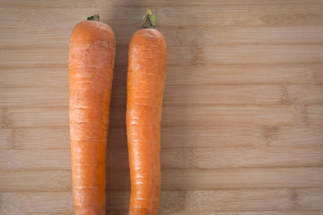 Top view of two fresh carrots on a wooden board in kitchen,closeup.