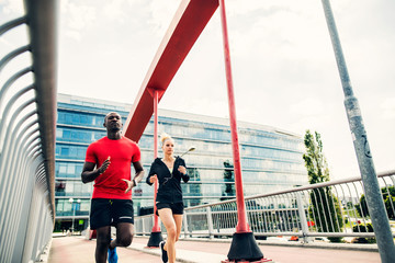 Canvas Print - Young couple in the city running on a bridge.