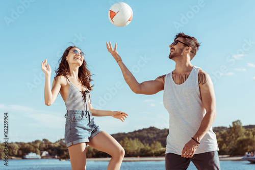 Zdjęcie XXL szczęśliwy aktywny mężczyzna i kobieta, gry w siatkówkę na plaży razem