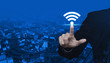 Businessman pointing to wi-fi button over modern city tower, street and expressway, Technology and internet concept