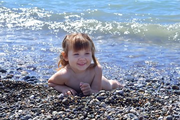 Baby girl lying on the beach at sea