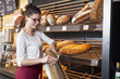© Lumi Images - Shop assistant in bakery packing bread into a bag