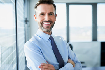 Canvas Print - Middle-aged businessman smiling at camera while in his office