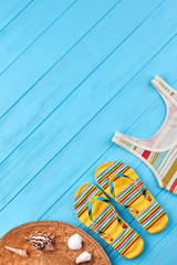 Wall Mural - Set of clothing and marine accessories. Female striped slippers and top, hat, seashells, blue wooden surface.