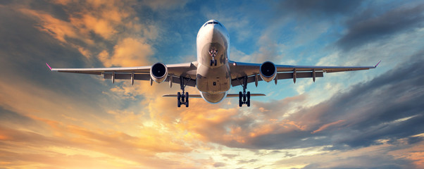 landing airplane. landscape with white passenger airplane is flying in the blue sky with clouds at c