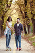 © Lumi Images - Young couple skateboarding through park