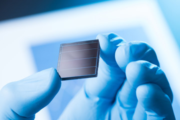 Scientist hold in hand small tile of new type efficient solar cell tile, solar technology research concept