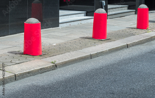 Fotomural Rote Begrenzungspoller auf einem Gehweg