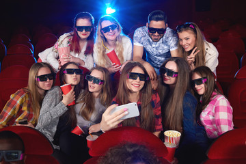 Wall Mural - Diverse group of friends wearing 3D glasses relaxing together at the cinema taking a selfie with a smart phone technology gadget connectivity mobility online social friendship entertainment concept.