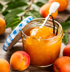 Wall Mural - Tasty fruit orange apricot jam in glass jar with fruits and vanilla sticks on wooden table. Closeup.