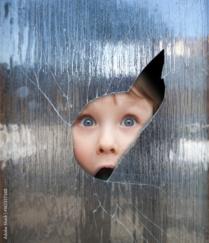 Fototapeta child looks through a window