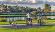 One woman on a exersise machine at an outdoor riverside gym in the early evening sunset.