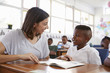 © Monkey Business - Volunteer teacher helping schoolboy at his desk, close up
