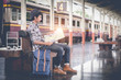 © itchaznong - Young travel sitting with map. travel bag at the train station.vintage filter effected .