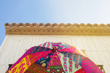Wall Mural - Colorful umbrella hanging on a mediterranean house balcony with blue sky in the background
