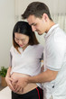 © DJ Creative Studio - Pregnant Women and Her Husband Hugging the Belly Taking Care with Love in the Room - Family Concept