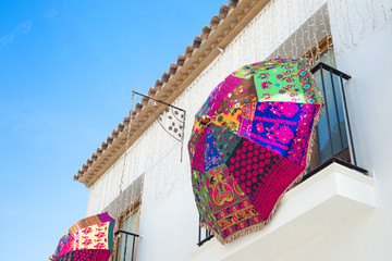 Wall Mural - Colorful umbrella hanging on a mediterranean house balcony with blue sky in the background