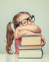 Wall Mural - beautiful cute little sulky girl leaning on thick books