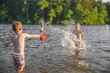 Children Have Fun And Play In The Water. Happy Boys Splashing In The Lake 