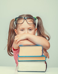 Wall Mural - beautiful cute little girl leaning on thick books and looking at camera