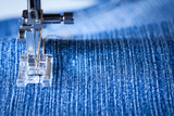 Fototapeta  - Foot Of Sewing Machine With Needle And Yellow Thread Sewing Fabric Of Denim Close Up.