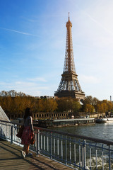 Young girl standing on a bridge, admiring the Eiffel tower in the last rays of the sun. Paris. France.