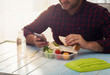 Man is eating healthy food sitting at wooden table