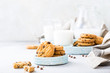 Stack of chocolate chip cookies on blue stone plate with glass of milk on light gray background. Selective focus. Copy space.