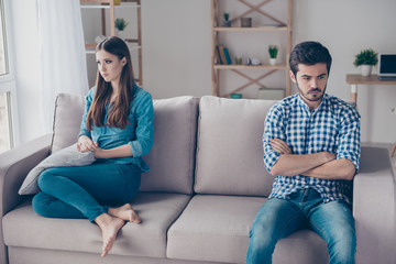 Poster - I am not talking to you! Mistrust and cheat problems. Annoyed couple is ignoring each other, sitting on the couch indoors at home with sad faces