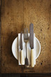 © Mint Images - Close up of plate with knives and fork and a serviette on a rustic wooden table.