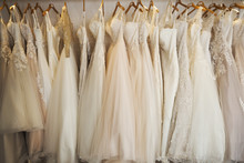 Rows Of Wedding Dresses On Display In A Specialist Wedding Dress Shop. A Variety Of Colour Tones And Styles, Fashionable Lace And Boned Bodices. 