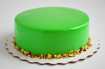 Modern French mousse cake with green mirror glaze. Picture for a menu or a confectionery catalog.