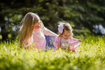 Family, mother and baby girl resting on nature, lying on grass
