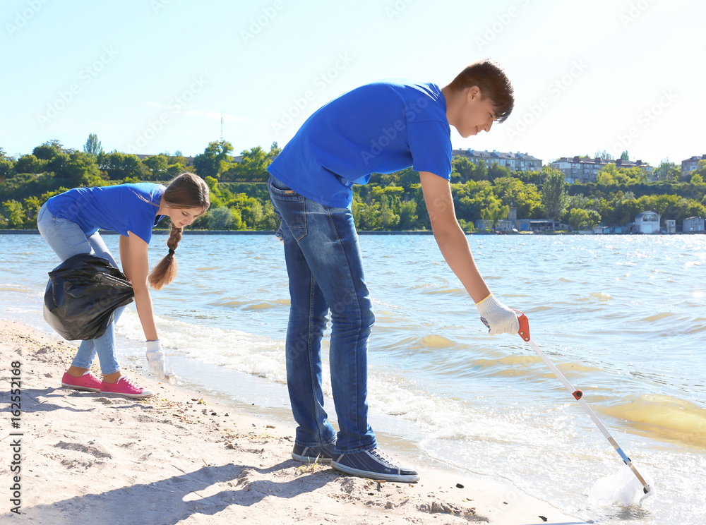 Young people cleaning beach area. Volunteer concept