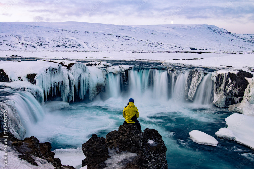 Adventurous man at Godafoss, Iceland in winter - obrazy, fototapety, plakaty 