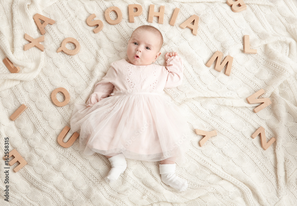 Cute baby with word SOPHIA lying on soft blanket. Choosing name concept
