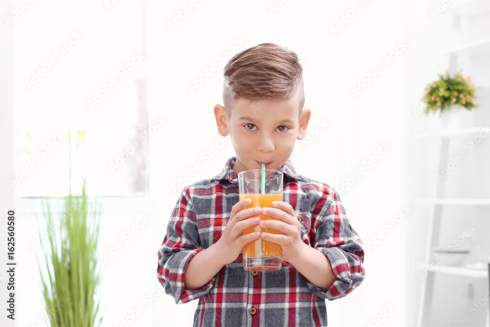 Cute little boy drinking juice at home