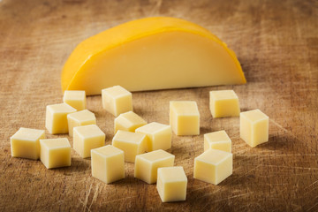 Cubes of yellow cheese stacked randomly on wood