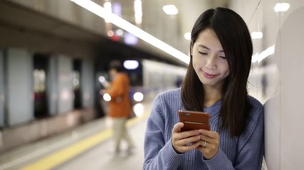 Sticker - Woman reading on cellphone at underground subway station