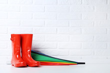 Red Rubber Boots With Umbrella On Brick Wall Background