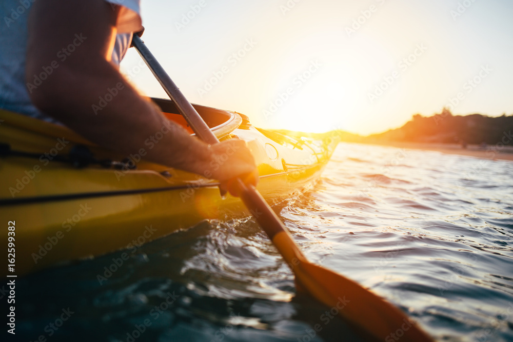 Close up of man holding kayak paddle at sunset - obrazy, fototapety, plakaty 