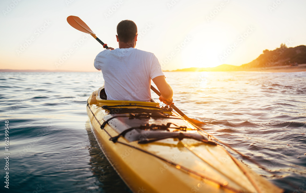 Rear view of kayaker man paddle kayak at sunset sea - obrazy, fototapety, plakaty 