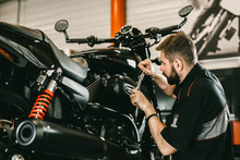 Professional Mechanic Working Screwdriver And Motorcycle Repairs. Handsome Young Man Repairing Motorcycle In Repair Shop.