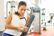 © Bojan - Young sporty woman with earphones and smartphone at the gym.