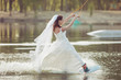 © Petro - Bride in a wedding dress and veil on her head is engaged in extreme sports, she is on a wakeboard.