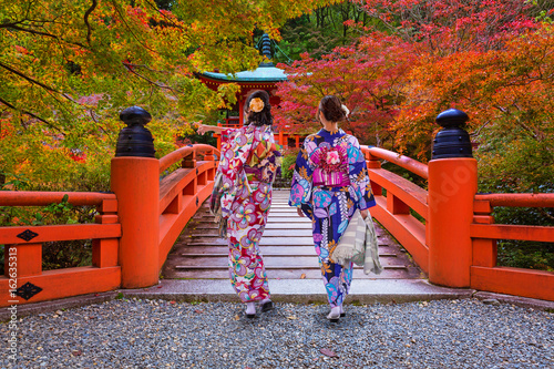 Cuadros en Lienzo Women in kimonos walking at the colorful maple trees in autumn, Kyoto