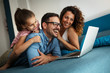 © BalanceFormCreative - Happy family lies on bed and watching something on laptop.Laughing and fun.