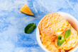 Homemade organic orange sorbet with orange slices and mint leaves. On a blue stone table, top close view, copy space