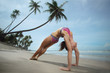 Woman doing yoga bridge pose on beach