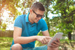 © nikolaborovic88 - Young man using tablet on park bench on a summers day